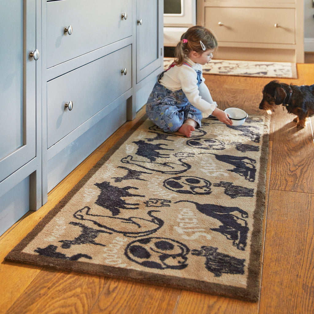 Lifestyle image of a girl and dog sar on a Hug Rug beige battersea dogs washable kitchen runner