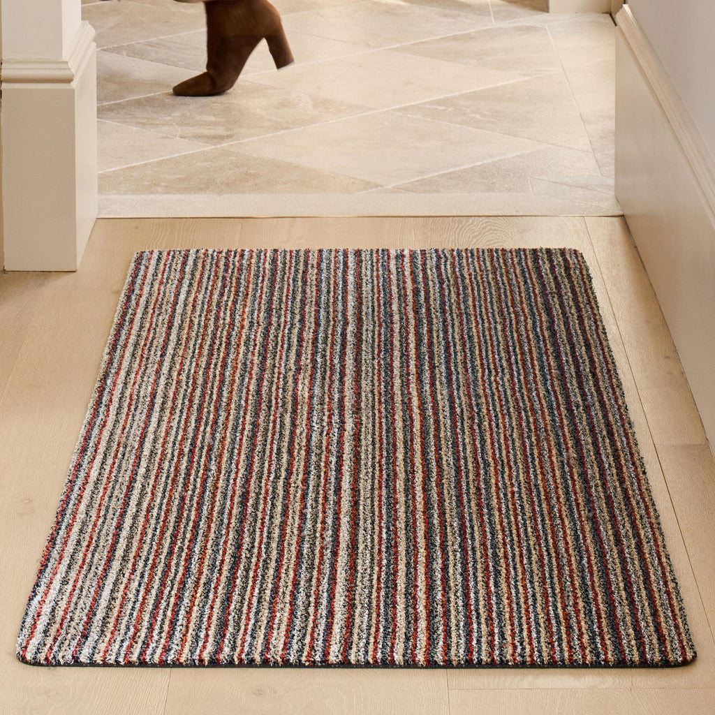 Candy Stripe Washable Runner- a 100% recycled material runner featuring a subtle striped pattern in shades of orange, red, beige, and grey.