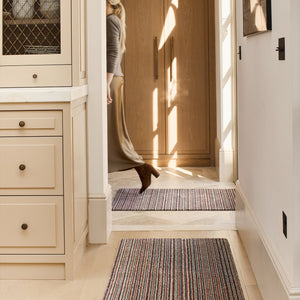 Candy Stripe Washable Runner- a 100% recycled material runner featuring a subtle striped pattern in shades of orange, red, beige, and grey.