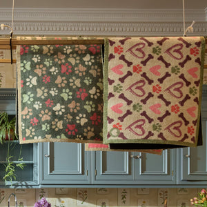 Hearts & Bones Runner - a 100% cotton runner featuring a pattern of bones, paw prints, and hearts in shades of burgundy, pink, green, and red.