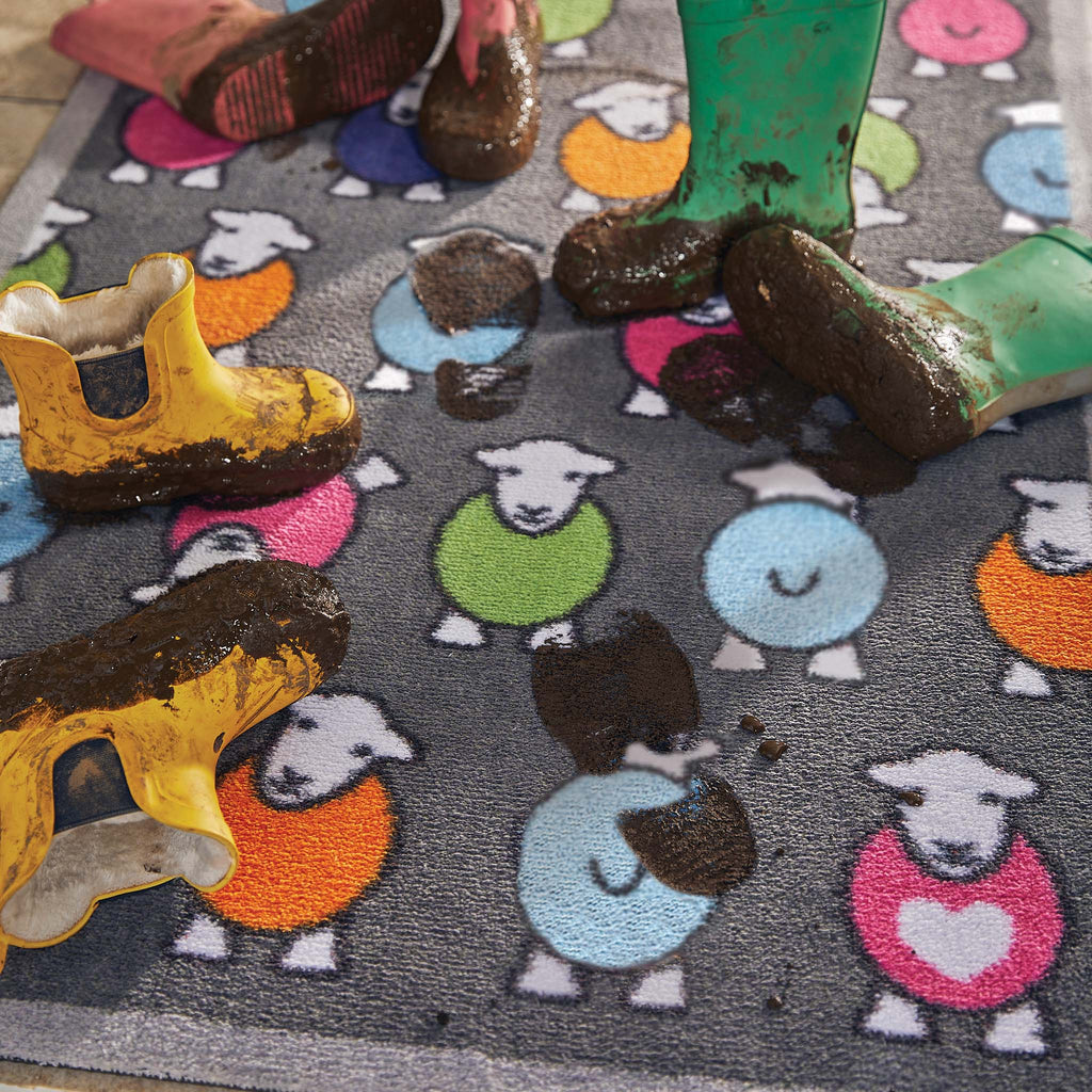 Lifestyle image of muddy wellies on a grey marra Herdy washable doormat from Hug Rug
