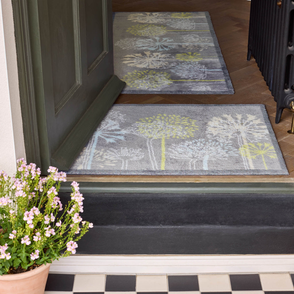 Two decorative doormats with floral patterns on a wooden floor.