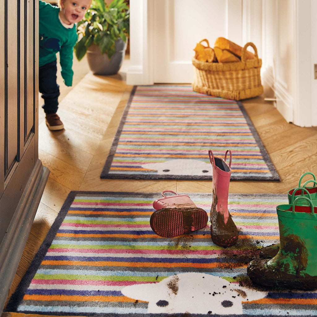 Lifestyle image of muddy wellies on a Peep Stripe Herdy washable doormat and washable hallway runner from Hug Rug