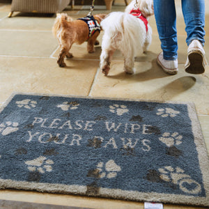 Lifestyle image of two dogs walking across a navy Pet 10 washable doormat from Hug Rug