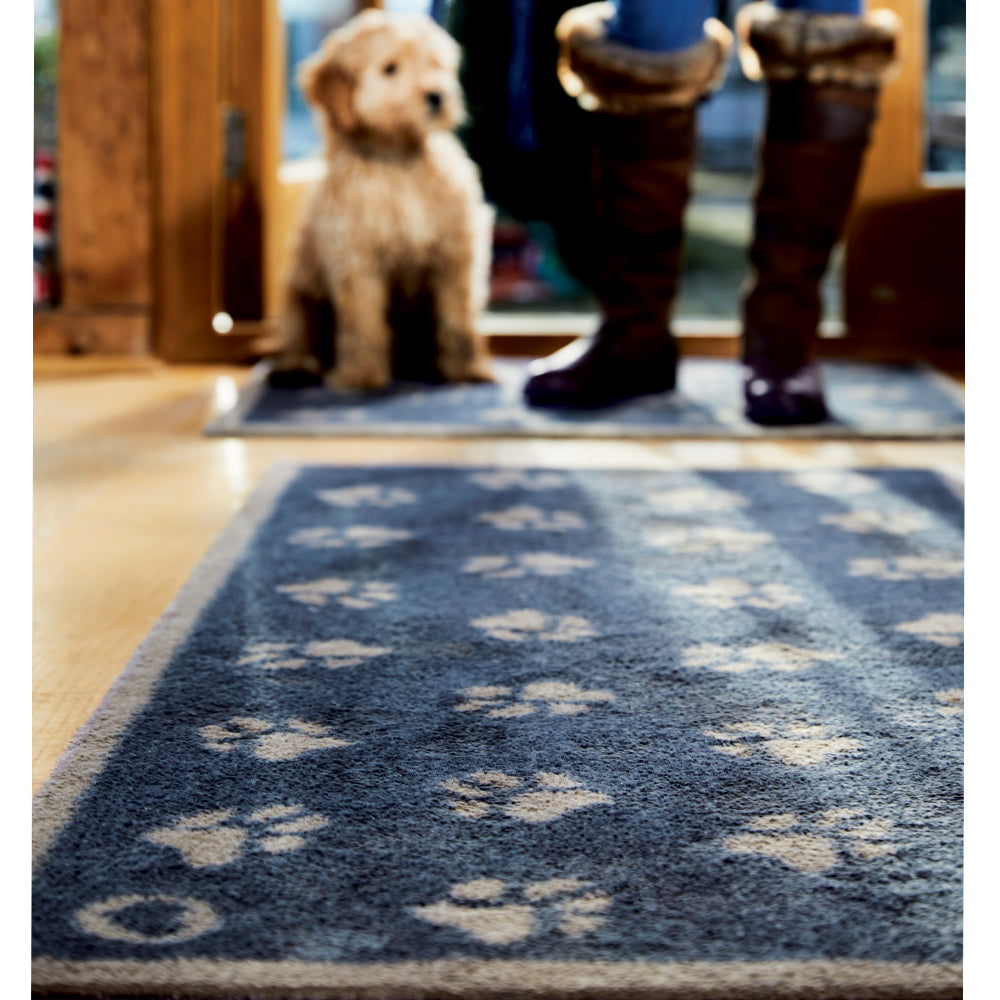 Lifestyle image of a dog and person walking across a navy Pet 10 washable doormat and runner from Hug Rug