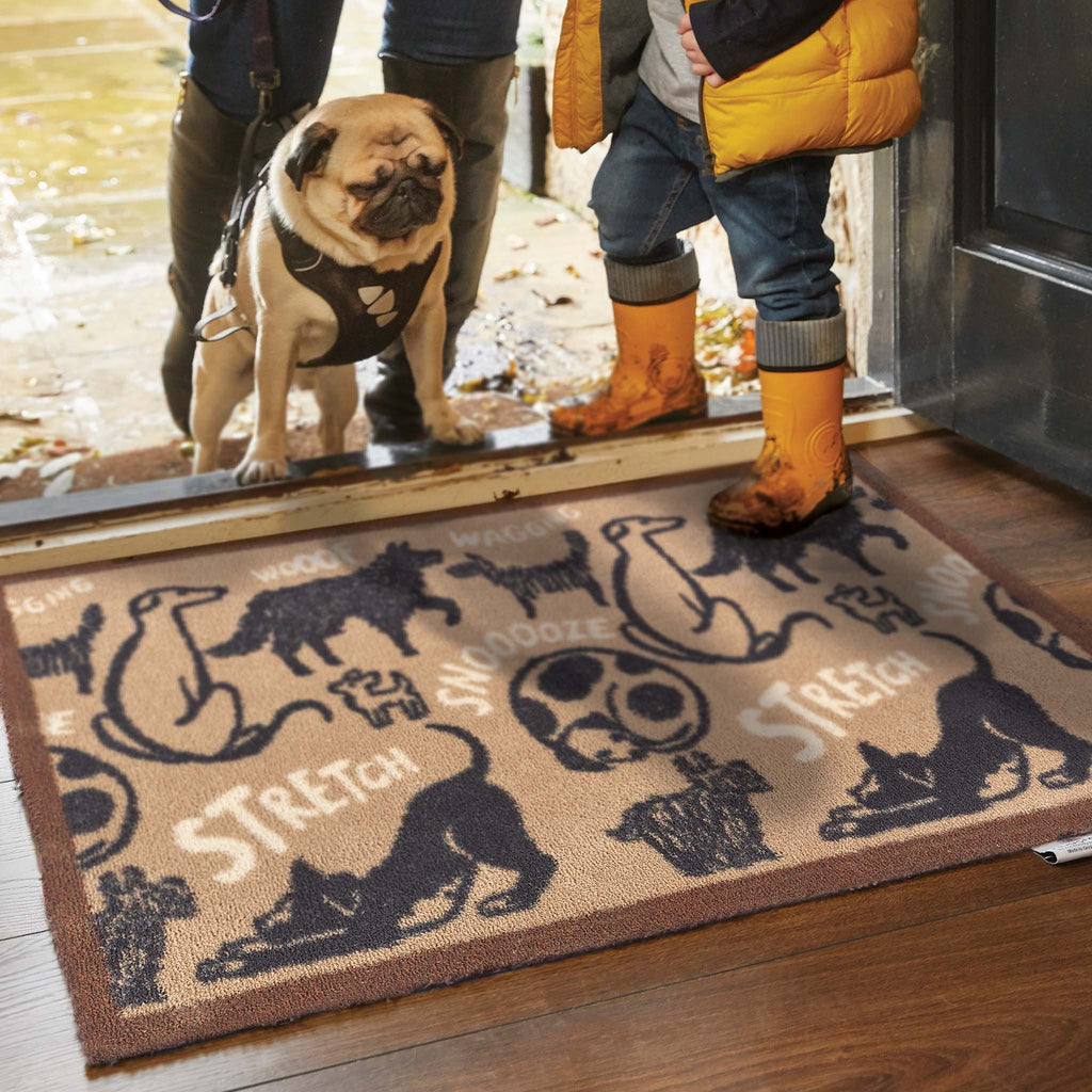 Lifestyle image of a dog and people walking onto a beige battersea dogs washable doormat