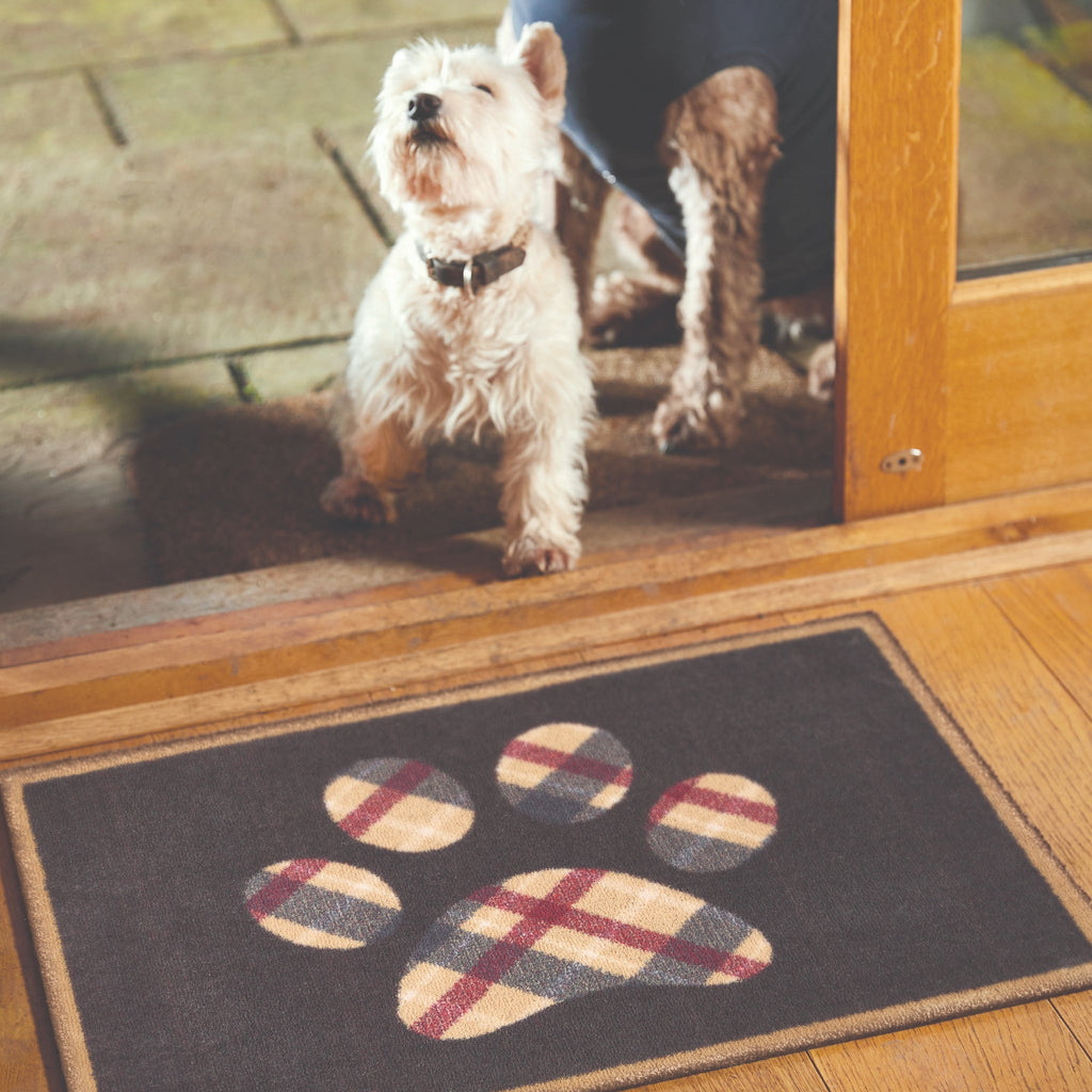 Lifestyle image of a dog and Hug Rug black tartan paw washable doormat