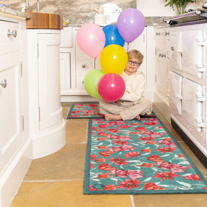 Tumbling Tulips Washable Runner- a 100% recycled cotton runner featuring tulips in rich reds, pinks and oranges, scattered across a soft teal backdrop.