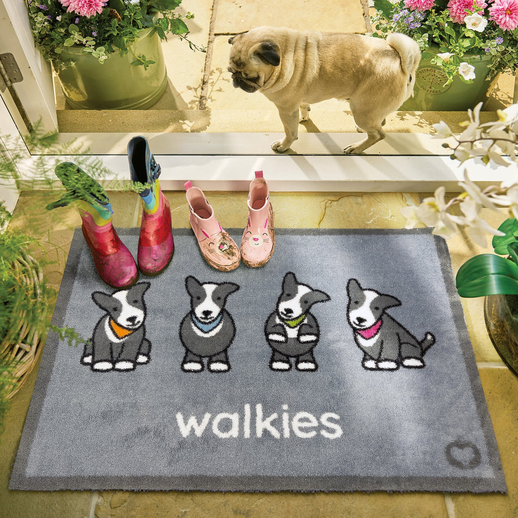 Lifestyle image of muddy wellies and a dog stood on a grey Herdy walkies washable indoor doormat from Hug Rug