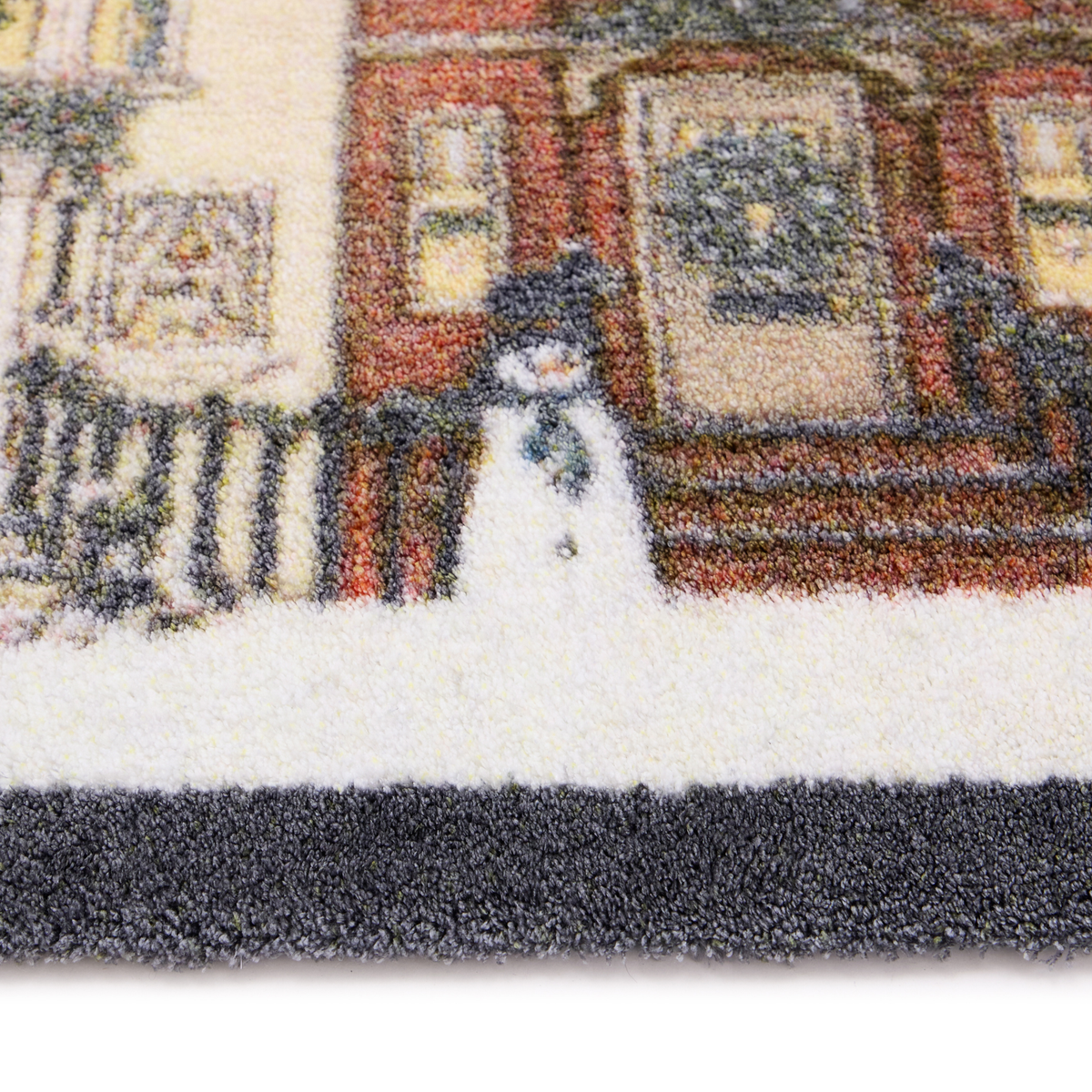 Close-up of a textured doormat featuring a winter city scene with a snowman standing in front of brick buildings.