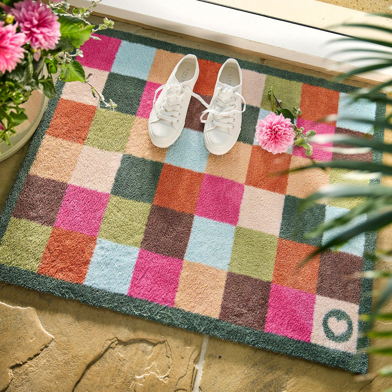 All Sorts Check Washable Doormat with colourful check design, styled in a doorway.