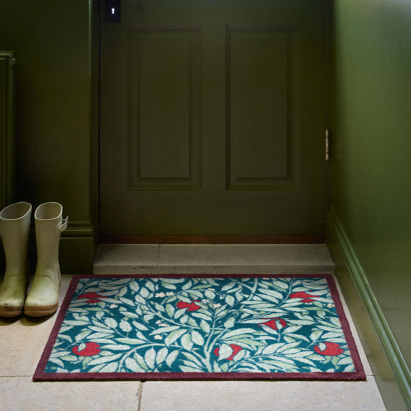 Ancient Apple Tree Midnight Washable Doormat with an apple tree design, styled by a green door. 