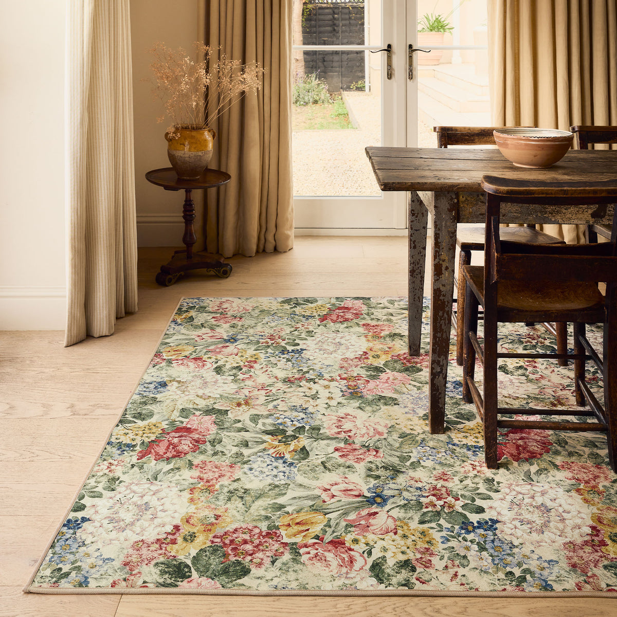 Antique Hydrangea & Rose Chintz Eco-Washable Rug with a floral design, styled under a wooden kitchen table.