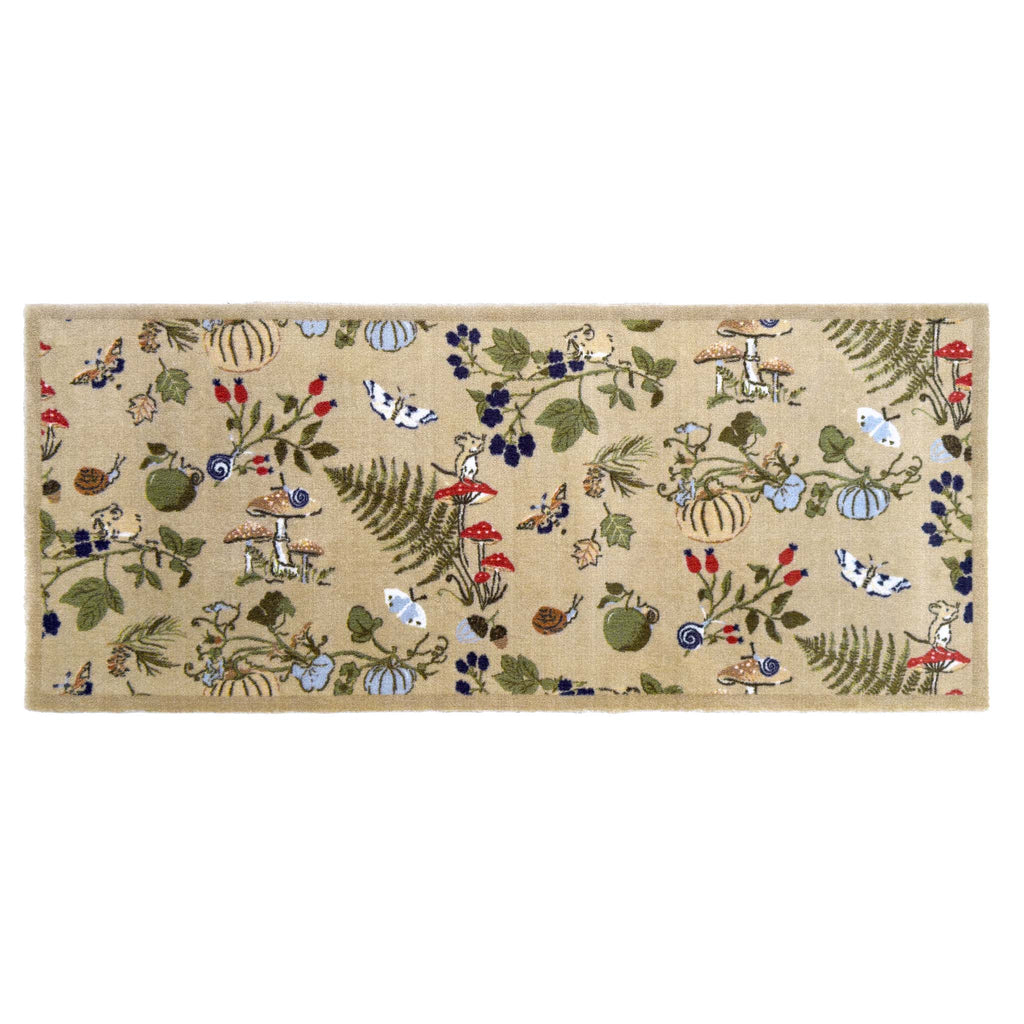 A rectangular runner with a beige background and a whimsical woodland pattern featuring rabbits, squirrels, acorns, berries, ferns, and small birds in green, blue, red, and brown.