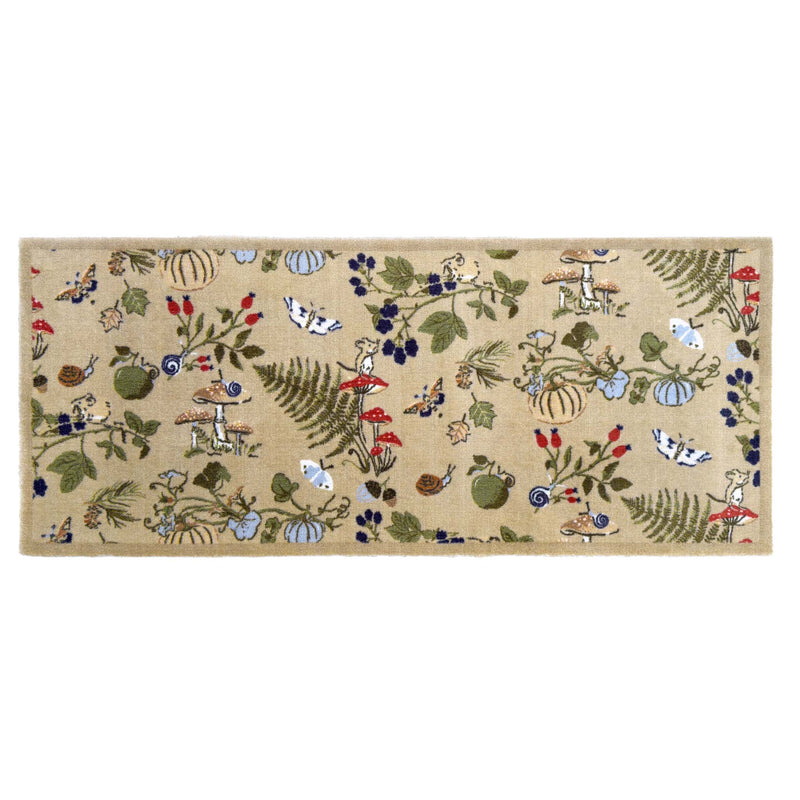 A rectangular runner with a beige background and a whimsical woodland pattern featuring rabbits, squirrels, acorns, berries, ferns, and small birds in green, blue, red, and brown.