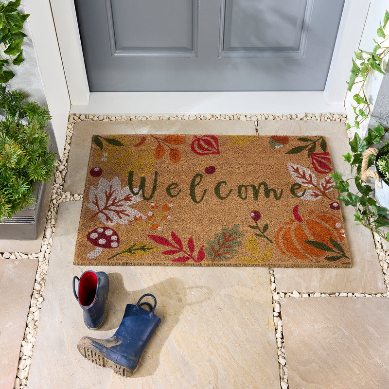 Discover the Autumnal Welcome Coir Doormat- a coir doormat featuring leaves, berries, pumpkins and mushrooms with a graphic font. 
