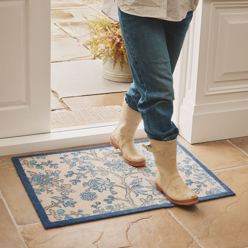 Azalea Walk Wedgwood Washable Doormat with a blue floral design, styled on tiled floor. 