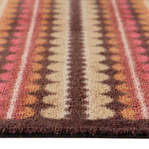 A close-up of a doormat with a Southwestern geometric pattern in brown, beige, pink, and orange, showing the textured pile and fringe edge.