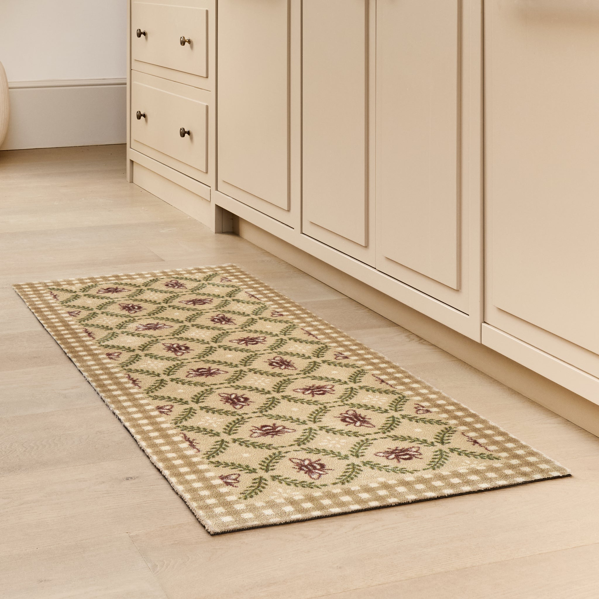Beehive Beige Charity Runner- 100% recycled cotton runner featuring a collection of bees surrounded by green laurel branches in an oval pattern.