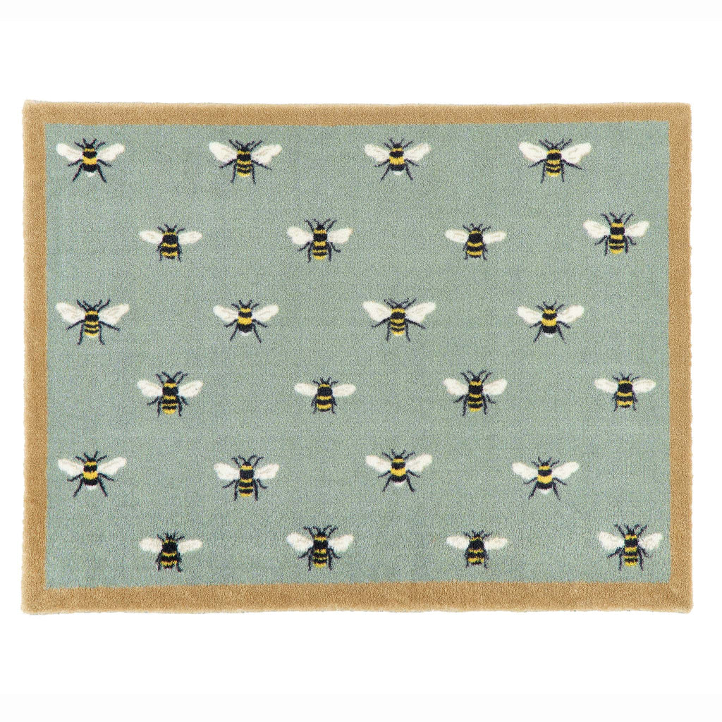 A rectangular doormat with a sage green background featuring a repeating pattern of bumblebees, finished with a natural coloured border.