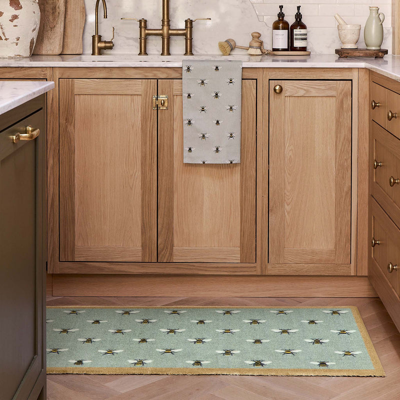 a teal runner with a bee patten in a modern kitchen by the sink.