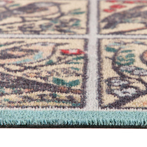 Close-up of a runner showing a cream background with a detailed multicolor floral pattern and a light blue fringed edge.