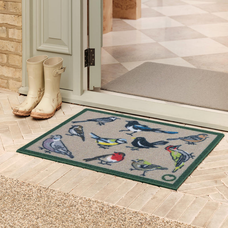 Bird Watcher Outdoor Recycled Doormat with a colourful bird design, styled in a doorway. 