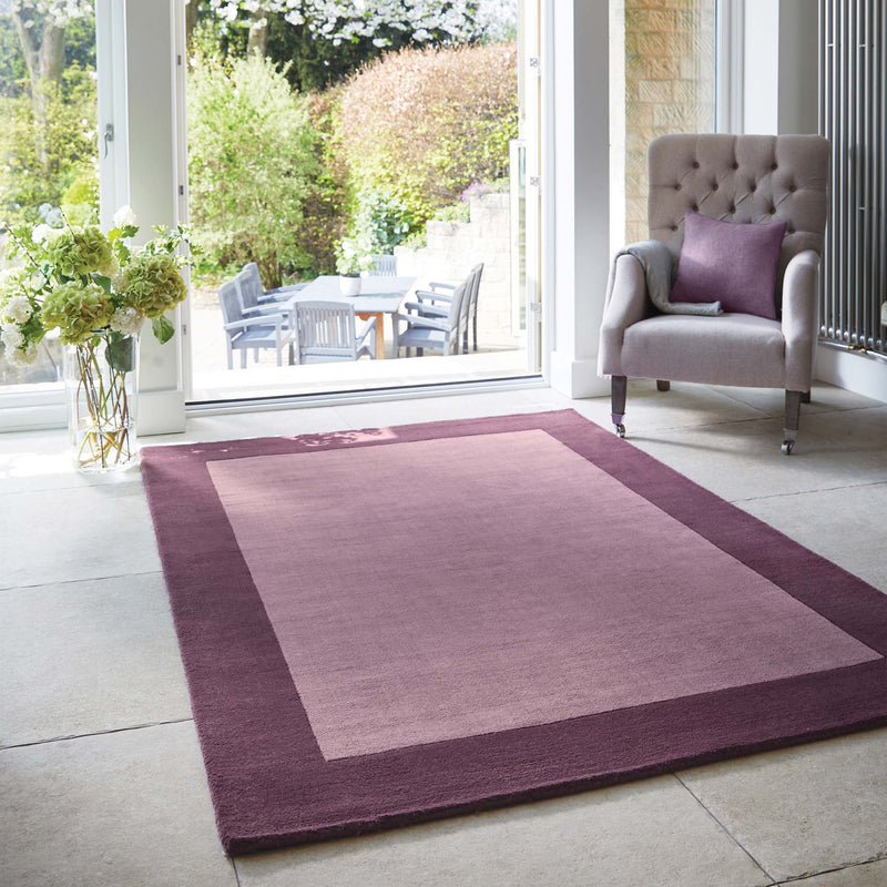 Borders Mauve Pink Purple 100% wool rug with a two-tone border design, styled in a conservatory.