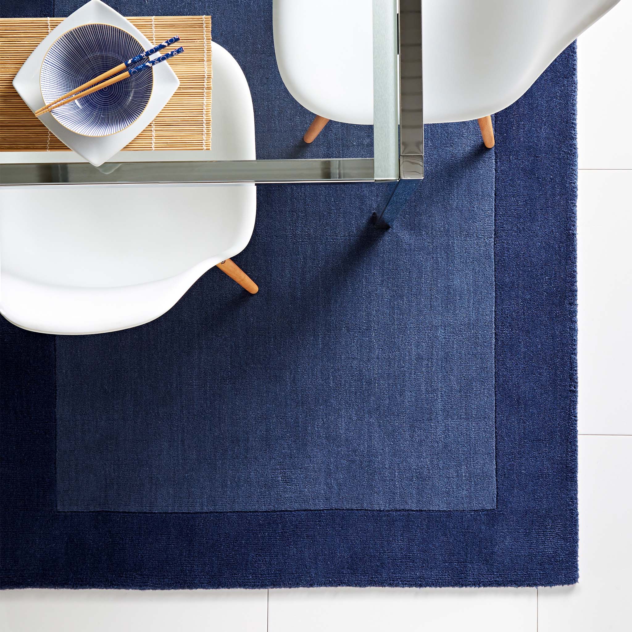 Borders Navy Blue 100% wool rug with a two-tone border design, styled in a dining room.