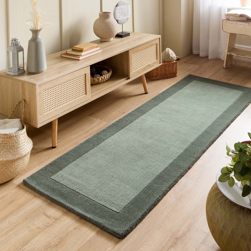 Borders Sage Green 100% wool runner with a two-tone border design, styled in a small room.