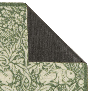 Close-up of a folded outdoor doormat showing a green and cream floral pattern on the top and side, with a dark charcoal backing visible on the underside against a white background.