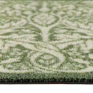 Close-up of a outdoor doormat  with a green and cream damask pattern, showing the pile height and the edge of the doormat. 