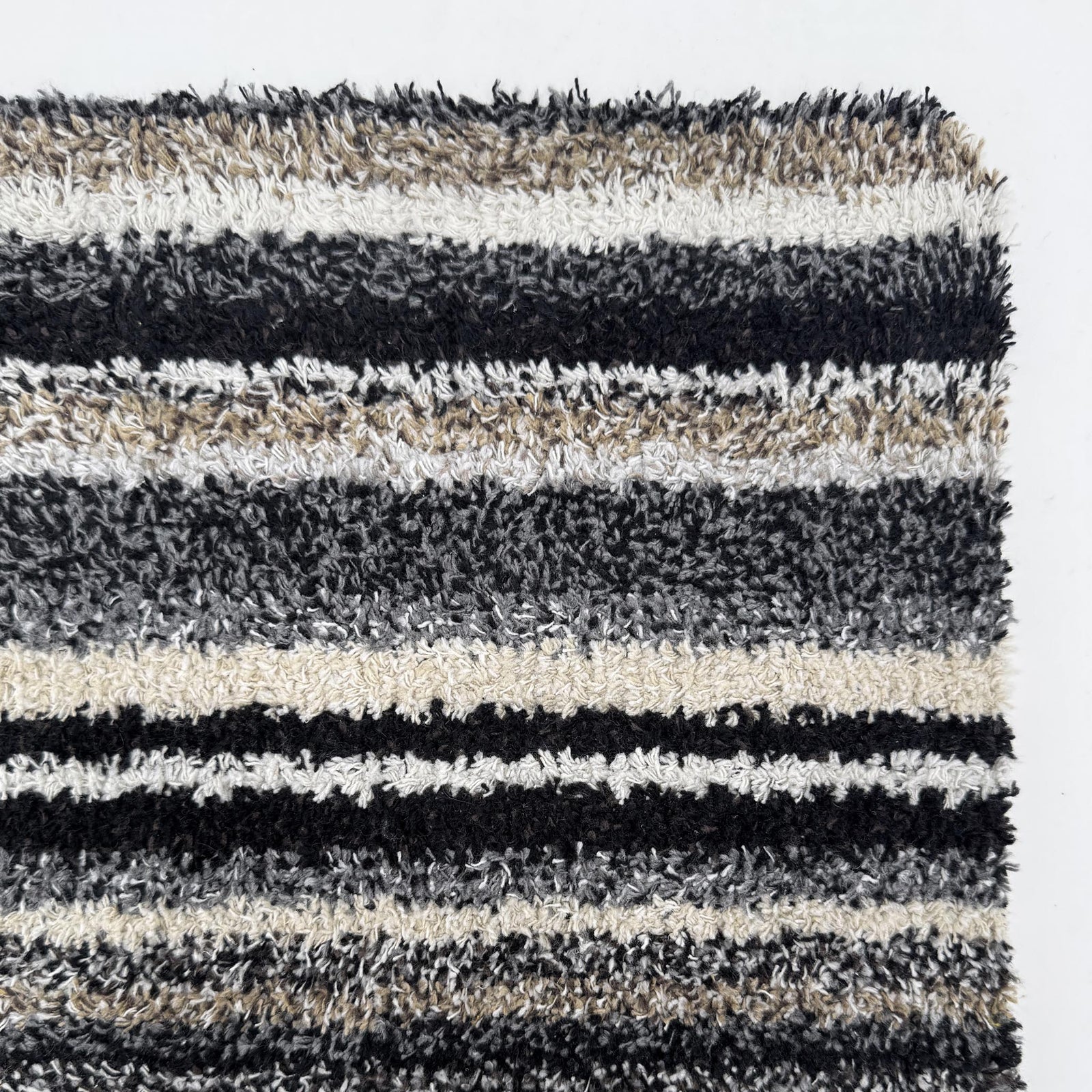 Candy Monochrome Washable Runner- a 100% recycled material runner featuring a subtle striped pattern in beige, grey, brown, black, and white. 