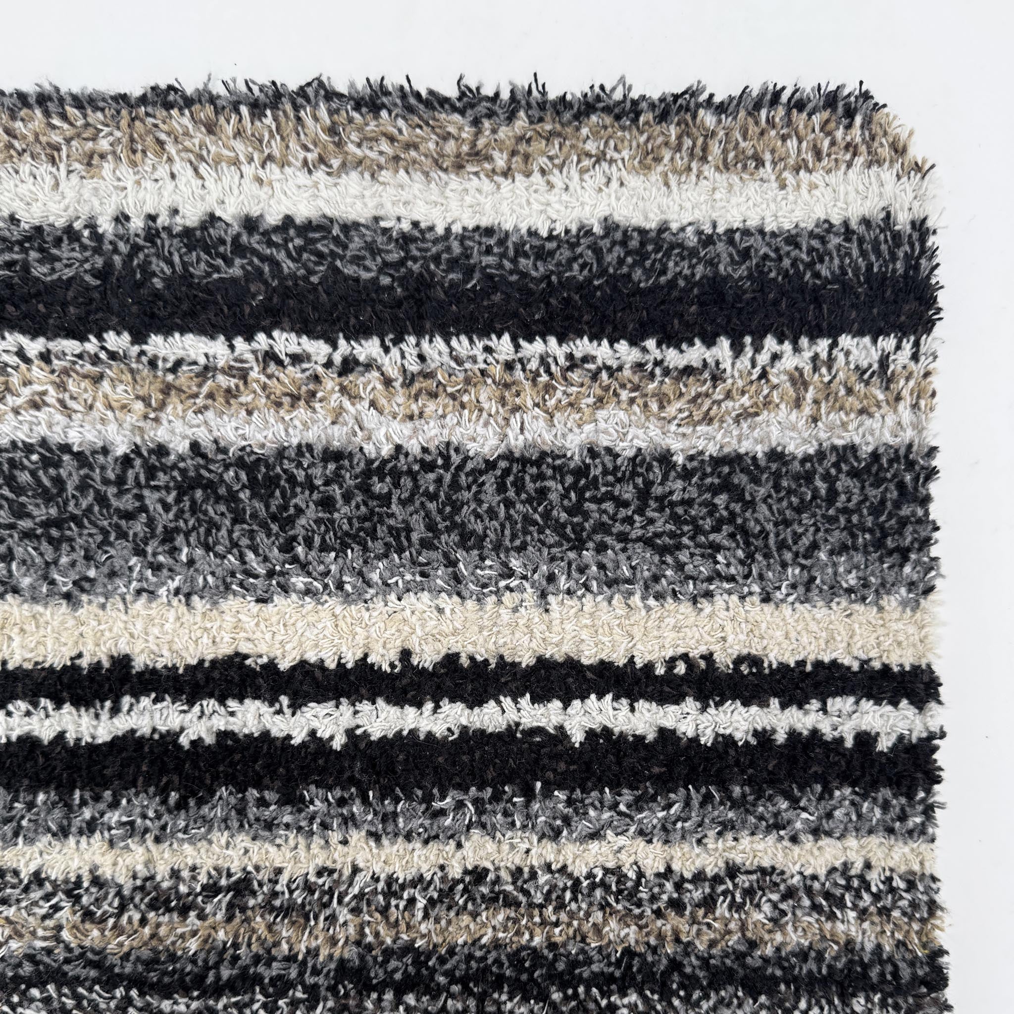 Candy Monochrome Washable Runner- a 100% recycled material runner featuring a subtle striped pattern in beige, grey, brown, black, and white. 