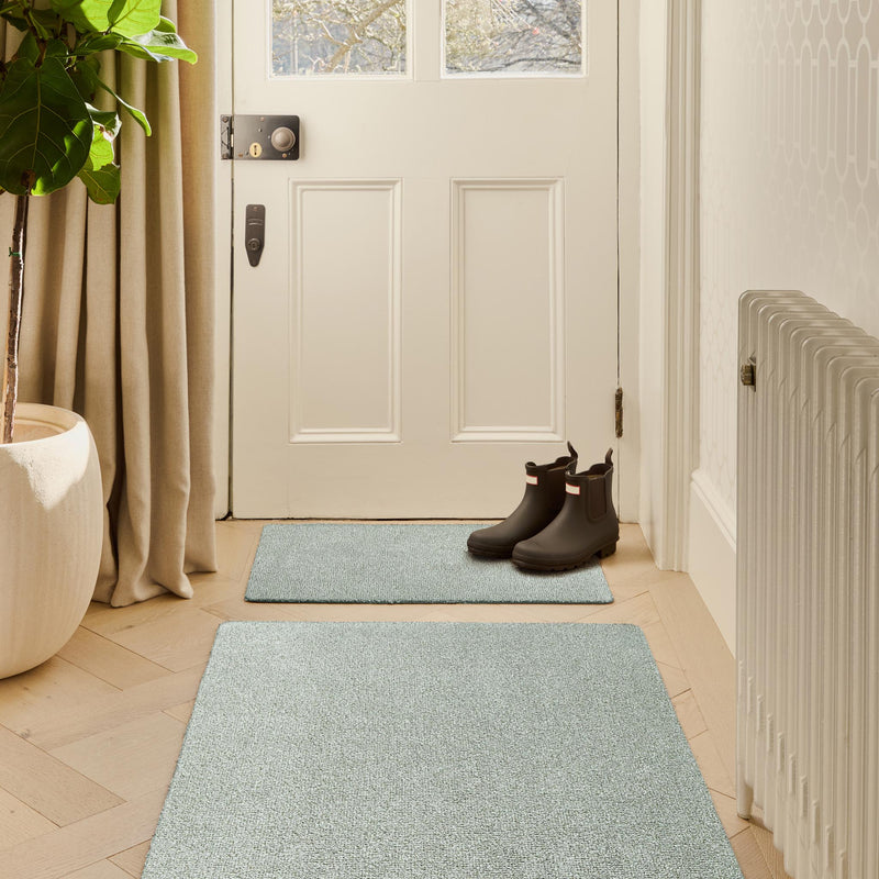 Plain Fleck Soft Green Washable Doormat in a green fleck design, styled in a entryway.