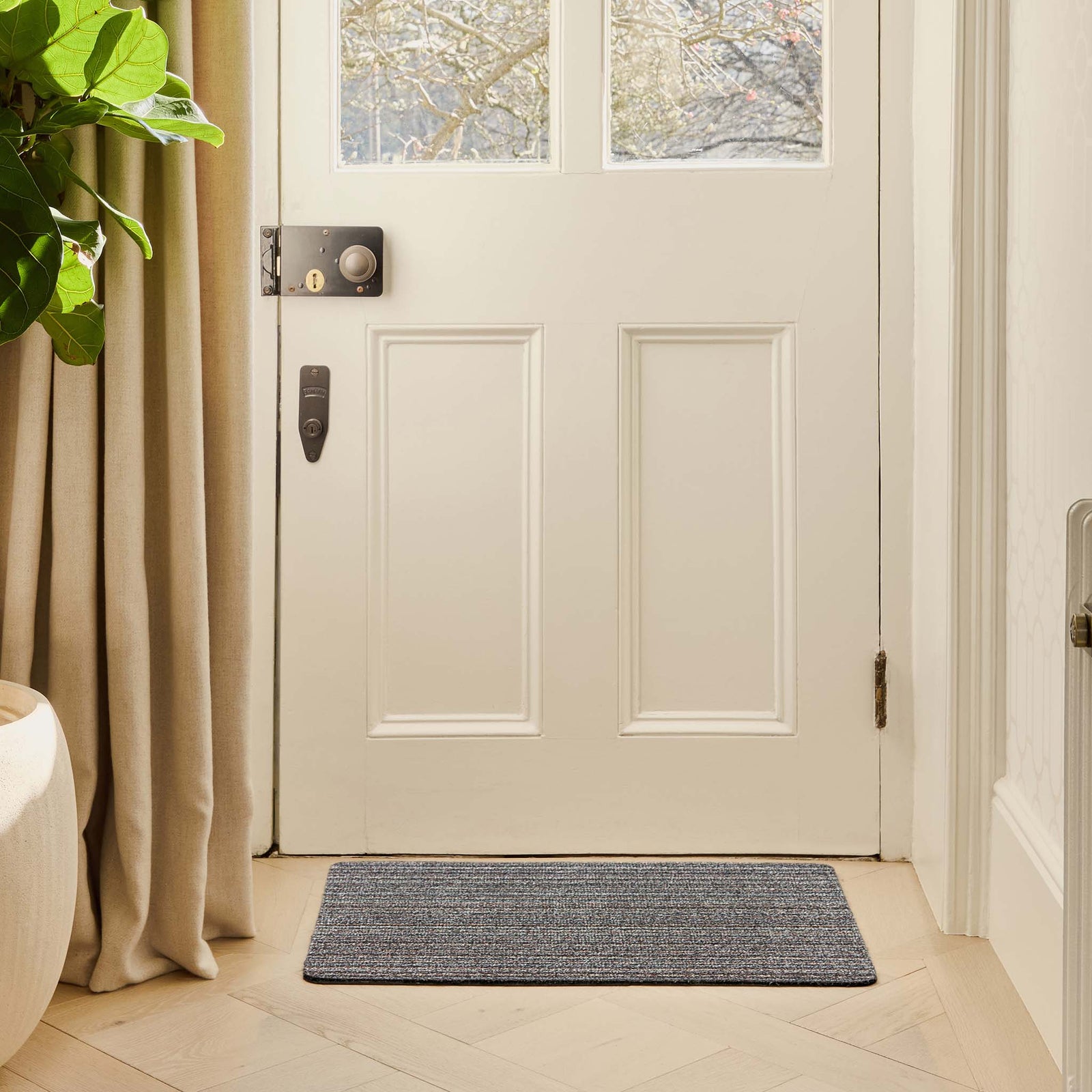 Candy Rocks Stripe Cotton Doormat with a striped design, styled in a doorway.