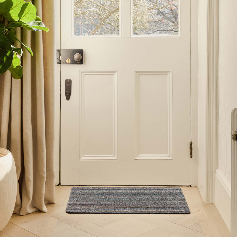 Candy Rocks Stripe Cotton Doormat with a striped design, styled in a doorway.
