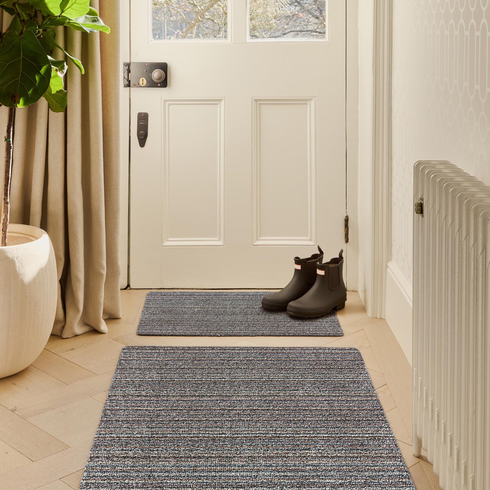 Candy Rocks Stripe Washable Doormat with a striped design, styled in a doorway.