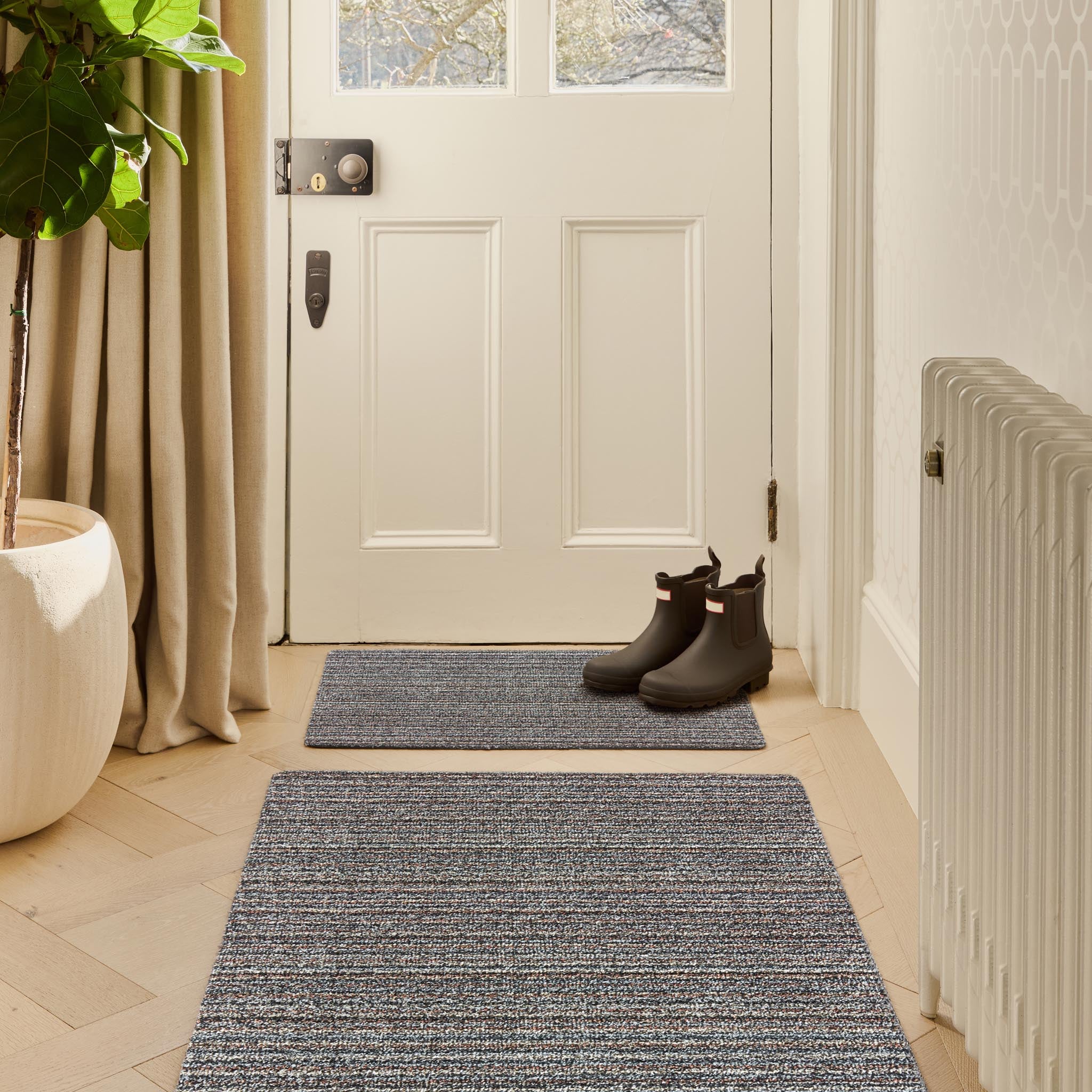 Candy Rocks Stripe Washable Doormat with a striped design, styled in a doorway.