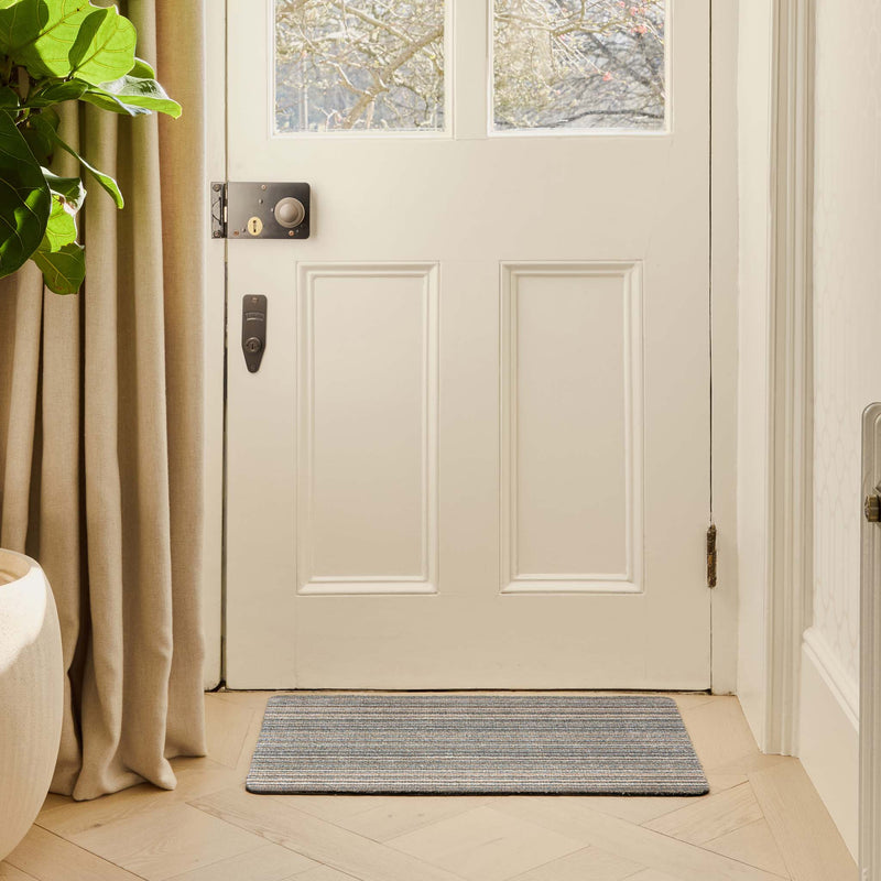 Candy Sand Stripe Doormat with a beige striped design, styled in a doorway.