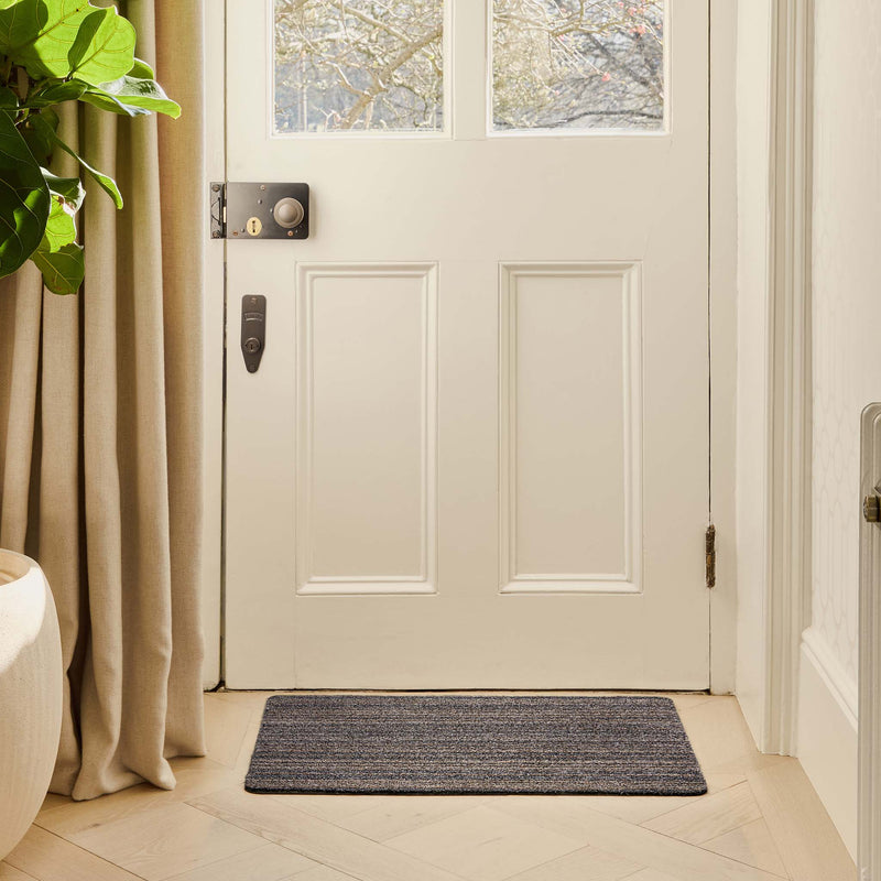 Candy Slate Stripe Cotton Doormat with a striped design, styled in a doorway.