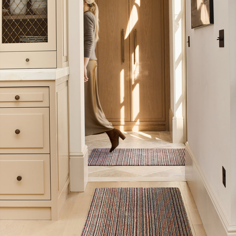 Candy Stripe Washable Runner- a 100% recycled material runner featuring a subtle striped pattern in shades of orange, red, beige, and grey.
