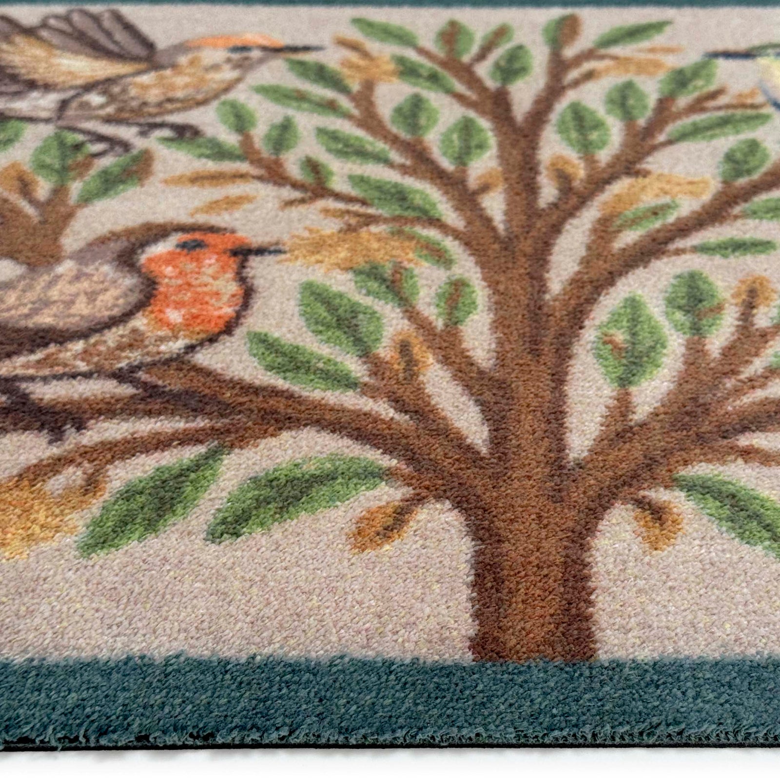 Close-up of Chorus Birds Beige Charity Doormat showing pile height and green blue border.