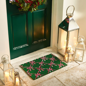 Discover the Christmas Festive Bows Coir Doormat- a coir doormat featuring pink bows against a green background. 