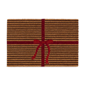 Discover the Christmas Gift Wrapped Coir Doormat- a coir doormat featuring a bright red bow and red lines giving the illusion of a present. 