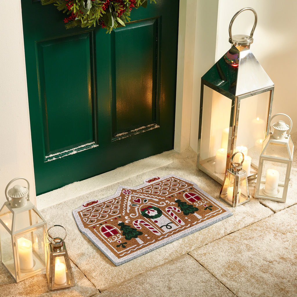 Discover the Christmas Gingerbread Cottage Coir Doormat- a coir doormat shaped as a gingerbread house decorated with sweets and icing. 