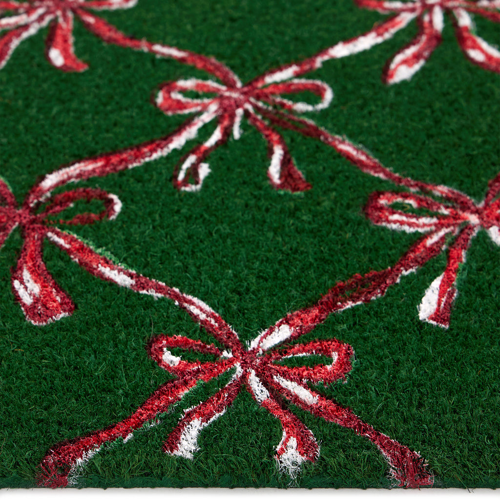 Discover the Christmas Festive Bows Coir Doormat- a coir doormat featuring pink bows against a green background. 