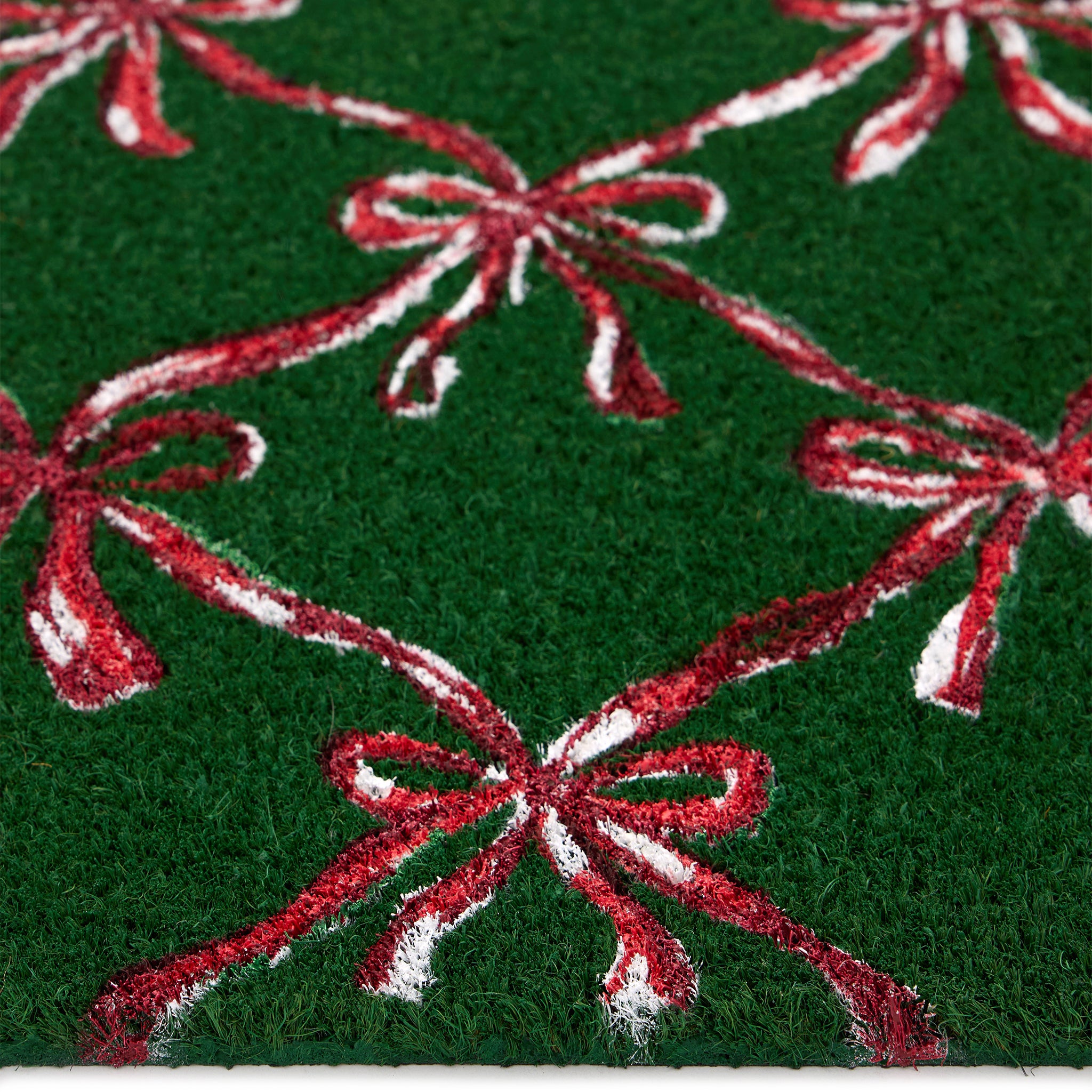 Discover the Christmas Festive Bows Coir Doormat- a coir doormat featuring pink bows against a green background. 