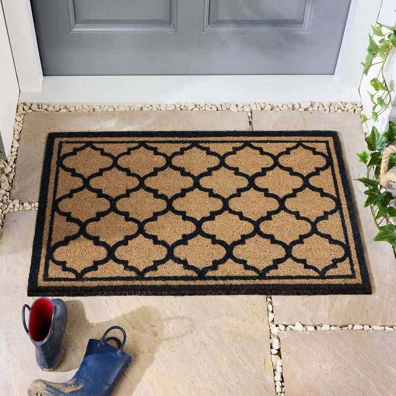 Moroccan Tile Coir Black Doormat with a geometric pattern, styled in a doorway.