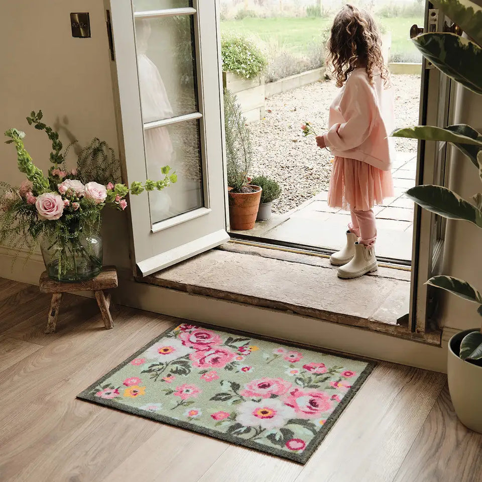 Country Rose Washable Green Pink Doormat with a floral design, styled in a doorway. 